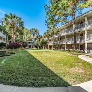 A view of an apartment complex with surrounding greenery and a well-maintained lawn.