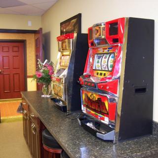 A lobby area with slot machines on a counter, featuring a red door and a flower arrangement.