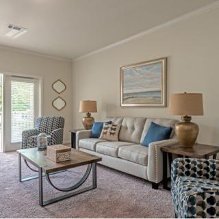 A cozy living room with a sofa, armchairs, and a coffee table, complemented by lamps and framed artwork.