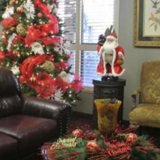 A festive living room decorated for Christmas, featuring a tree adorned with red and white ornaments and a Santa Claus figure.