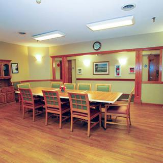 A well-lit conference room with a large wooden table and chairs arranged around it.