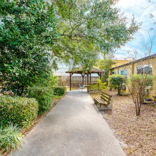 A serene pathway leads through a lush garden, inviting visitors to relax and enjoy the natural surroundings.