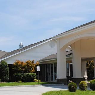 A modern building entrance with a landscaped front area under a clear sky.
