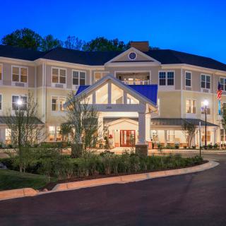 A beautifully lit three-story building with manicured landscaping at night.