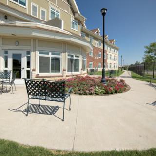 A sunny view of a building exterior with outdoor seating and landscaped walkway.