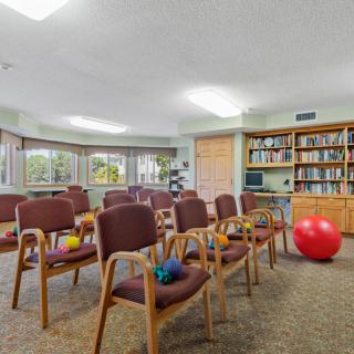 A meeting room with chairs and exercise equipment, featuring bookshelves and large windows.