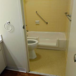 A simple and clean bathroom featuring a toilet and bathtub with yellow walls.