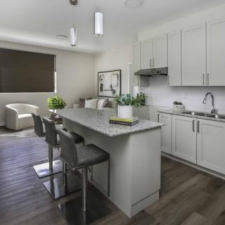 A modern kitchen with sleek white cabinets, a central island with bar stools, and contemporary pendant lighting.