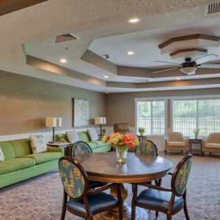 A cozy living room with stylish furniture, including a round table and chairs, sofas, and a ceiling fan.