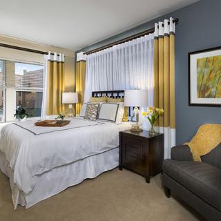 A modern bedroom with stylish decor, featuring a cozy bed, elegant curtains, and contemporary artwork.