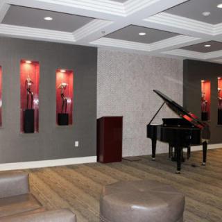 A stylish lounge area featuring a grand piano and decorative wall displays of awards.