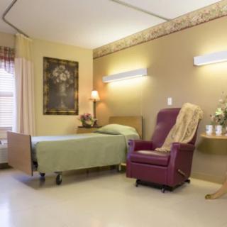 A cozy healthcare room with a bed and chair, decorated for comfort.