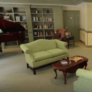 A cozy living room with sofas, a piano, and bookshelves.