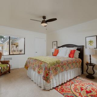 A cozy and inviting bedroom featuring a beautifully decorated bed, stylish furniture, and warm natural lighting.