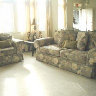 A bright living room featuring a floral-patterned sofa and armchair.