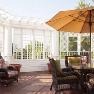 Sunny patio with wicker furniture and an umbrella for shade.