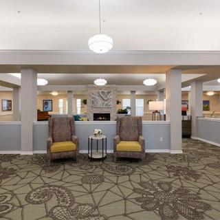A well-lit lobby with comfortable armchairs and a stylish carpet.