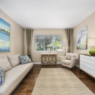 A cozy living room featuring a sofa, armchair, and artwork with natural lighting.