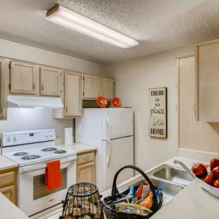 A cozy kitchen with wooden cabinets, a white stove and refrigerator, and decorative items on the countertop.