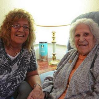 Two women smiling while seated in a comfortable living room setting.