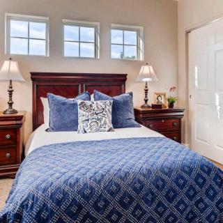 A cozy bedroom with a neatly made bed, blue bedding, and elegant wooden furniture.