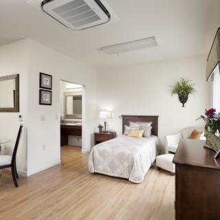 A minimalist bedroom with a single bed, wooden floors, and tasteful decorations.