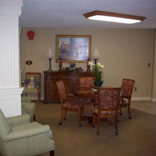 A cozy room with a table and chairs, decorated with artwork and lamps.