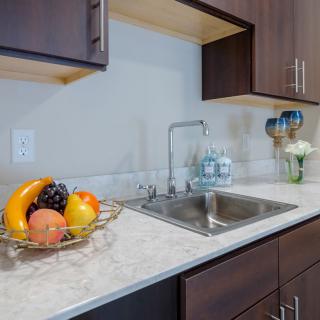 A modern kitchen with a clean countertop, featuring a fruit bowl and stainless steel sink.