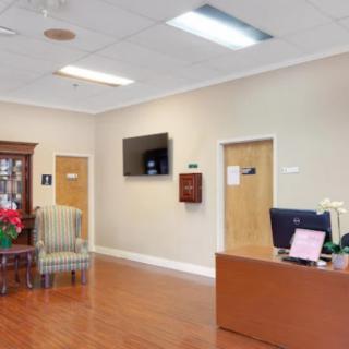 A reception area featuring a desk, chairs, and a television on the wall.