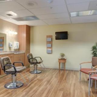A cozy waiting room with chairs, mirrors, and a television.