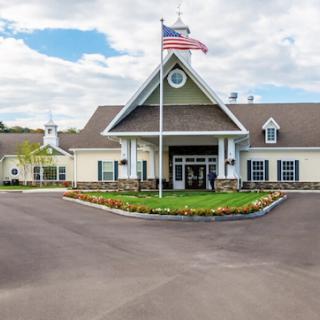 A well-maintained entrance to a building with an American flag and beautiful landscaping.