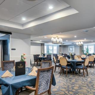 An elegantly set dining area with tables, chairs, and chandeliers.