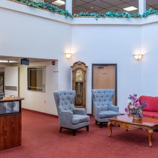 A brightly lit lobby with comfortable seating and a grandfather clock.
