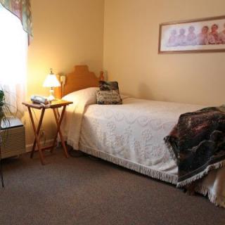 A cozy bedroom with a single bed and soft lighting.