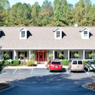 A quaint house with a well-maintained front yard and parked cars in the driveway.