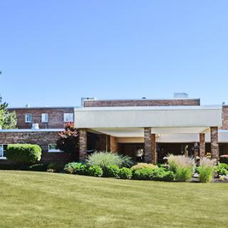A well-maintained building surrounded by lush greenery under a clear blue sky.