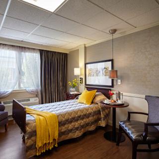 A cozy and modern bedroom with warm decor, featuring a comfortable bed, seating area, and ample natural light.