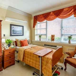 A well-decorated hospital room with warm colors and wooden furniture.