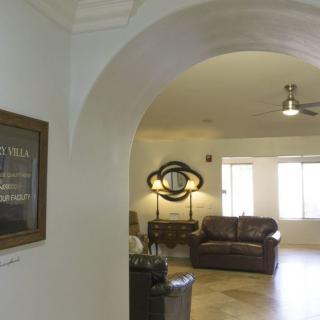 A view of a cozy living room through an archway, featuring a sofa, lamp, and wall art.