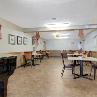 An empty dining area with neatly arranged tables and chairs, decorated with wall art and pendant lights.