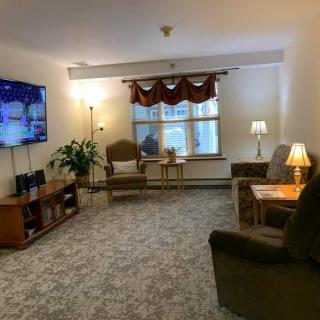 A cozy living room with a TV, armchairs, and ambient lighting.