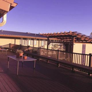 A spacious outdoor deck with a table and benches under a pergola.