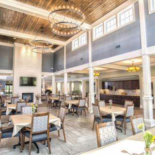 A spacious and bright restaurant interior with elegant chandeliers and neatly arranged tables.