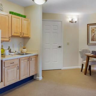 A cozy apartment kitchen with wooden cabinets, a sink, and a small dining area.