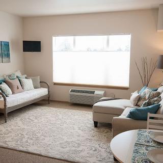 A cozy and modern living room with light-colored furniture and large window.