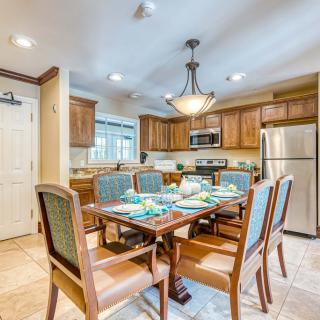 A modern kitchen and dining area with wooden cabinets, a dining table set for six, and stainless steel appliances.