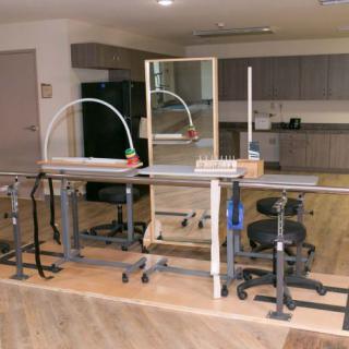 A rehabilitation room equipped with parallel bars and other therapy equipment.