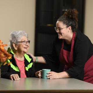 A caregiver interacts warmly with an elderly woman, fostering a sense of connection and support.