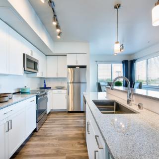 A modern kitchen with stainless steel appliances, white cabinets, and granite countertops.