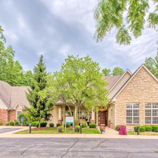 A suburban house with a well-maintained garden and trees lining the driveway.